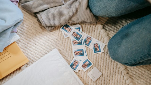 Stamps scattered on a blanket next to envelopes