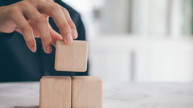 Neutral colored cube blocks being; a woman's hand is arranging them