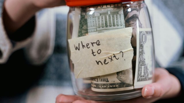Woman's hands holding jar of cash labeled with sticky note that reads "Where next?"