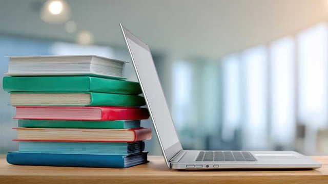 A stack of books with a laptop computer open next to them