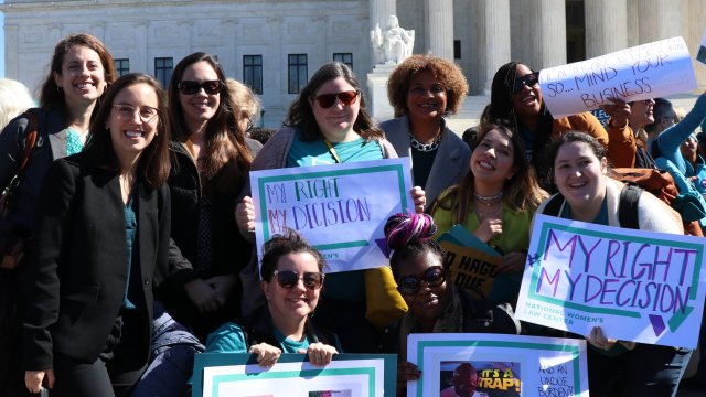 Group of women gathered outdoors with protest signs stating "My Right, My Decision."